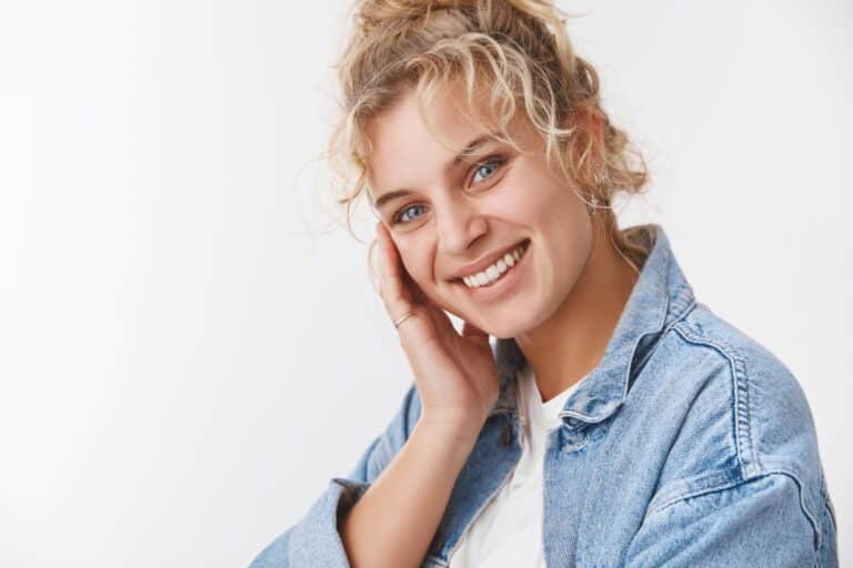 Lächelnde Frau mit lockigem Haar in Jeansjacke.